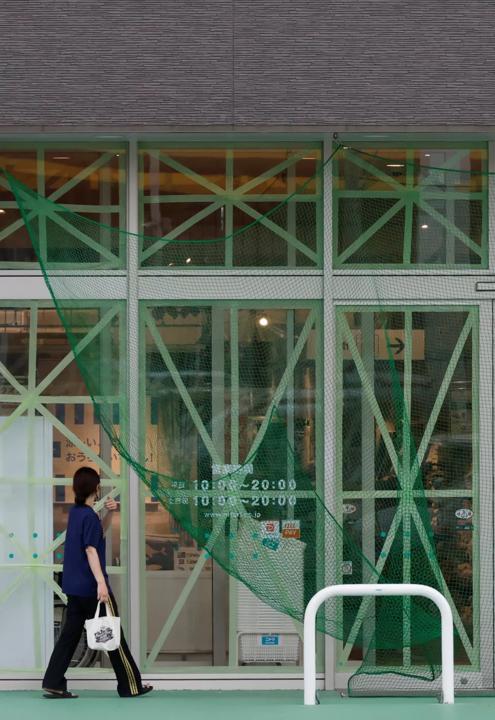 A woman enters a shop covered with a wind-proof net and duct-taped windows to prevent damage from Typhoon Bavi as it approaches, in Ishigaki, Japan, July 9, 2026. REUTERS/Kim Kyung-Hoon