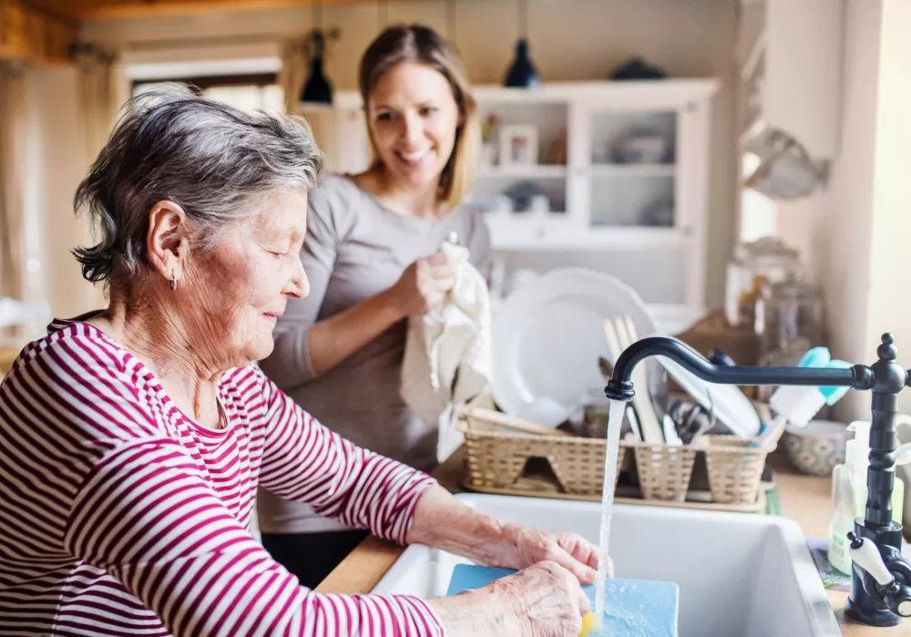 A happy elderly grandmother with an adult granddaughter at home, washing the dishes. / Foto: Halfpoint Getty Images/istockphoto