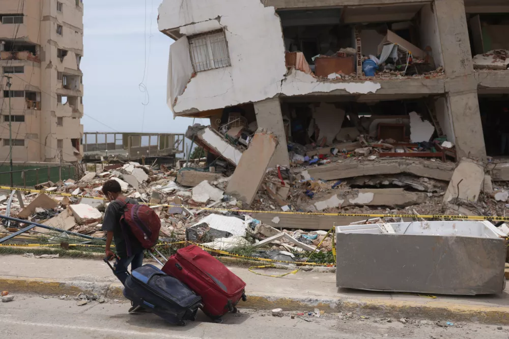 A child carries suitcases outside a Mision Vivienda housing building damaged by the June 24 earthquakes, in Catia la Mar, La Guaira state, Venezuela, July 9, 2026. REUTERS/Leonardo Fernandez Viloria