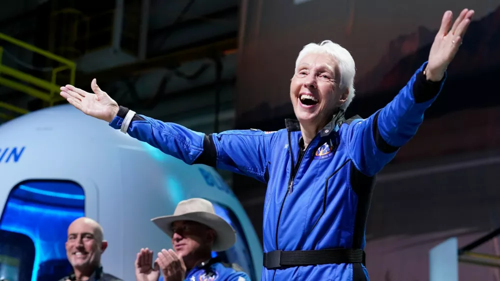 FILE - Wally Funk, right, describes her flight experience as Mark Bezos, left, and Jeff Bezos, left, center, applaud in the spaceport near Van Horn, Texas, July 20, 2021. (AP Photo/Tony Gutierrez, File)