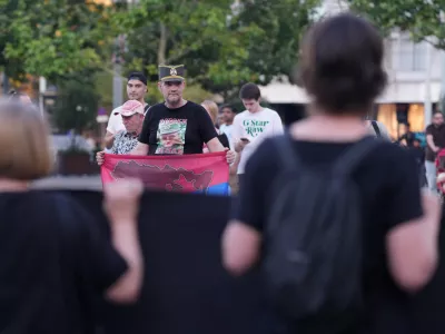 A man wearing a T-shirt with a picture of former Bosnian Serb wartime general Ratko Mladic, holds a Serbian flag and stands opposite members of anti-war organization "Women in Black" during a meeting to mark the 31st anniversary of the Srebrenica tragedy in Belgrade, Serbia, Friday, July 10, 2026. (AP Photo/Darko Vojinovic)