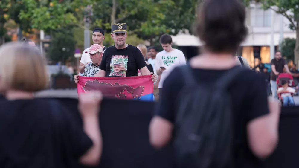 A man wearing a T-shirt with a picture of former Bosnian Serb wartime general Ratko Mladic, holds a Serbian flag and stands opposite members of anti-war organization "Women in Black" during a meeting to mark the 31st anniversary of the Srebrenica tragedy in Belgrade, Serbia, Friday, July 10, 2026. (AP Photo/Darko Vojinovic)