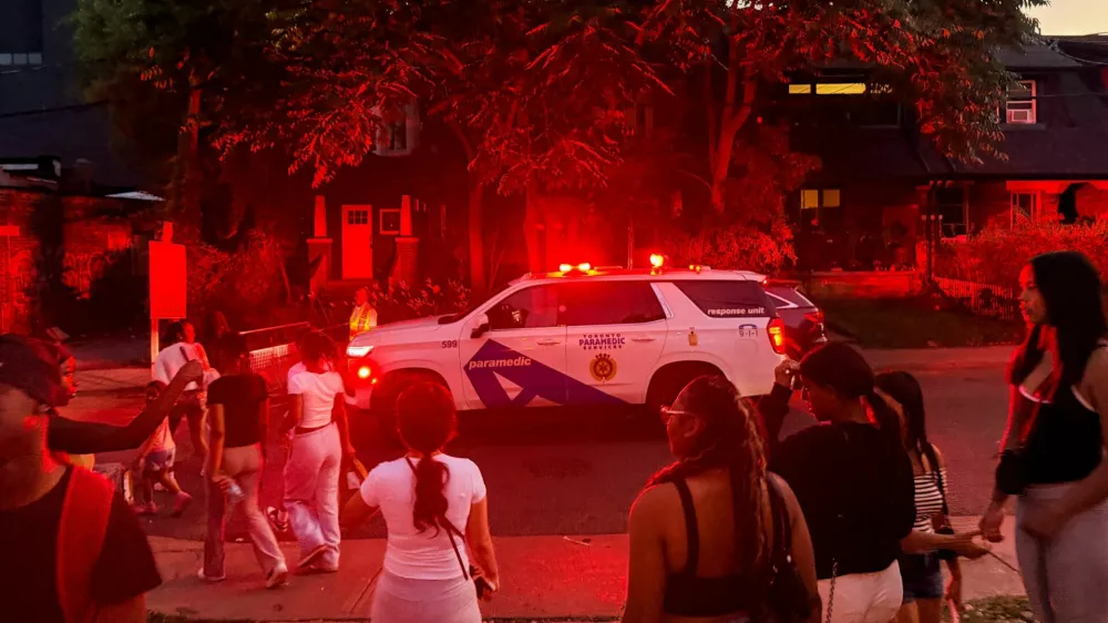 A police vehicle makes its way as people gather near the scene after a deadly shooting, at a salsa-themed street festival in Toronto, Ontario, Canada, July 11, 2026. Picture taken using a mobile phone. REUTERS/Cole Burston