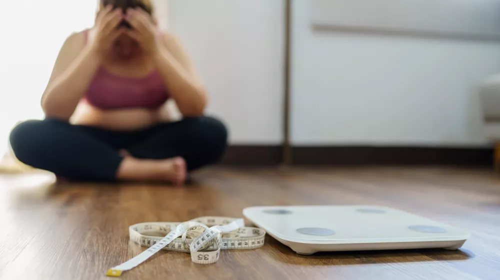 Obese Woman with fat upset bored of dieting Weight loss fail&Acirc;&nbsp; Fat diet and scale sad asian woman on weight scale at home weight control.