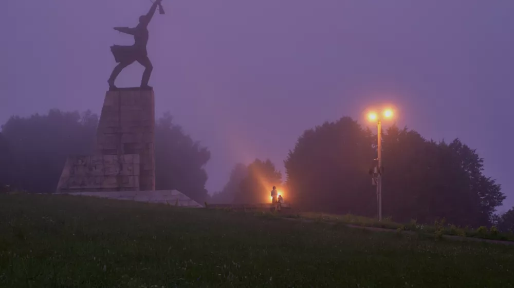 A couple stand near the monument "Peremilovskaya Heights", in Peremilovo village, about 70 kilometers (44 miles) north from Moscow, Russia, before sunrise, Sunday, July 12, 2026. (AP Photo/Alexander Zemlianichenko)