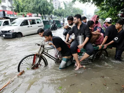 People cross a flooded street on tricycle following torrential rain in Dhaka, Bangladesh, July 12, 2026. REUTERS/Mohammad Ponir Hossain   TPX IMAGES OF THE DAY