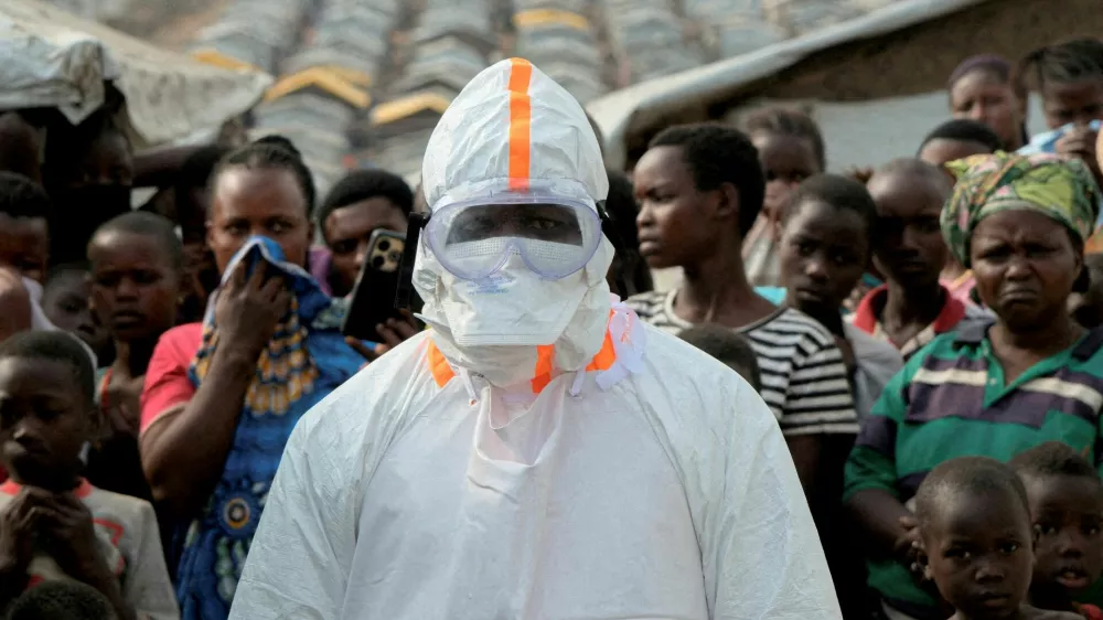 FILE PHOTO: A health worker in personal protective equipment stands near displaced people waiting for the burial of suspected Ebola victims at the Kigonze displaced persons camp, one month after an outbreak was declared, in Bunia, eastern Democratic Republic of Congo, June 18, 2026. REUTERS/Gradel Muyisa Mumbere/File Photo