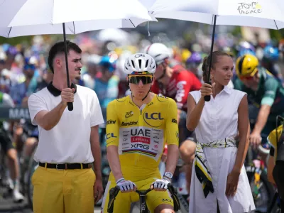 Slovenia's Tadej Pogacar, wearing the overall leader's yellow jersey, is shielded from the sun ahead of the start of the ninth stage of the Tour de France cycling race with start in Malemort and finish in Ussel, France, Sunday, July 12, 2026. (AP Photo/Mosa'ab Elshamy)