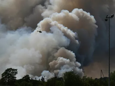 A fire fighting helicopter in action as wildfires are seen in the Fontainebleau forest region, about 60 kilometers (37 miles) south of Paris, France, Monday, July 13, 2026. (AP Photo/Emma Da Silva)