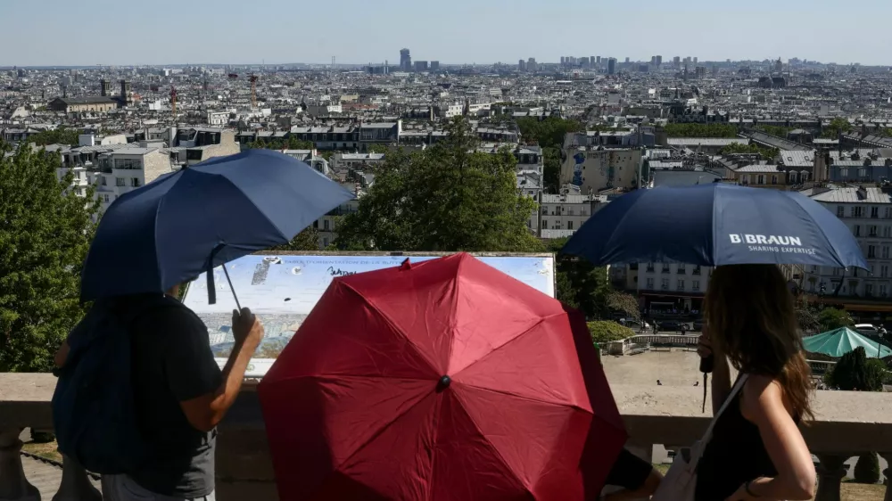 People shelter under umbrellas in front of the Sacre Coeur in Montmartre during high temperatures amid a heatwave in Paris, France, July 12, 2026. REUTERS/Tom Nicholson