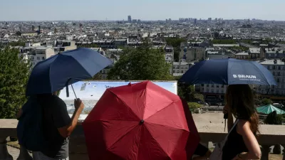 People shelter under umbrellas in front of the Sacre Coeur in Montmartre during high temperatures amid a heatwave in Paris, France, July 12, 2026. REUTERS/Tom Nicholson