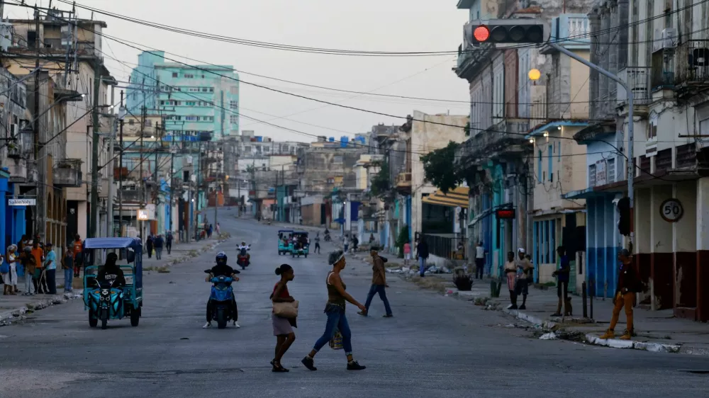 People cross a street as Cuba's national power grid is restored following its collapse, which marked the third major outage in nine days, in Havana, Cuba, July 15, 2026. REUTERS/Norlys Perez