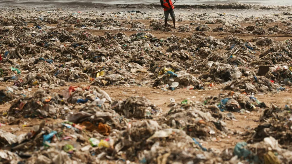 A worker cleans up garbage washed onto a beach after high tide in Mumbai, India, July 15, 2026. REUTERS/Francis Mascarenhas