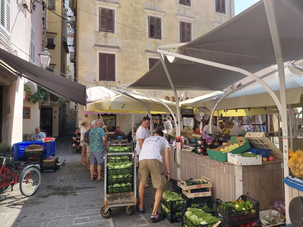 Jutranji utrip na zelenjavni tržnici, ki jo čez dan zapolnijo turisti, ki kupujejo sadje po kosih. 