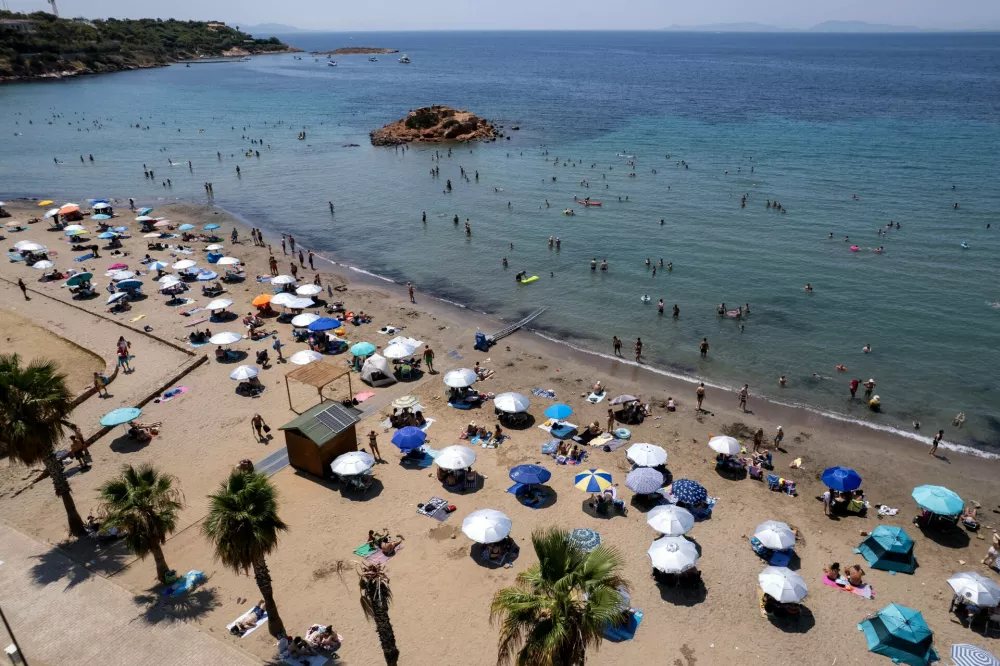 People gather at a beach during a day where temperatures reached 39 Celsius degrees, (102.2 Fahrenheit), at Kavouri suburb, south of Athens, Greece, on Sunday July 19, 2026. (AP Photo/Yorgos Karahalis)