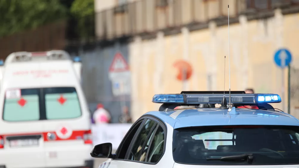 police car with blue flashing lights on it while escorting an ambulance to go to the hospital after the accident