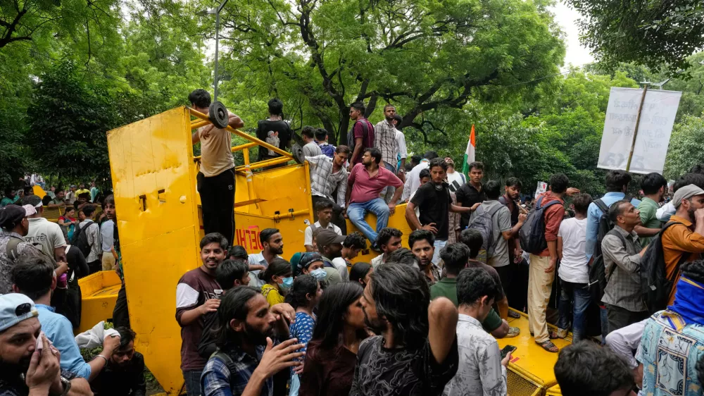 Supporters of the Cockroach Janta Party shout anti government slogans sitting on a police barricade as they they attempt to march toward India's Parliament, demanding the resignation of the education minister, in New Delhi, India, Monday, July 20, 2026. (AP Photo/Manish Swarup)