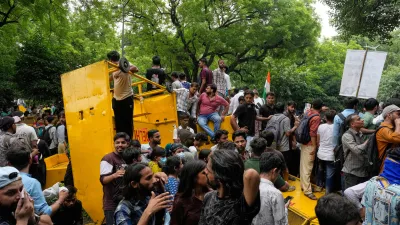 Supporters of the Cockroach Janta Party shout anti government slogans sitting on a police barricade as they they attempt to march toward India's Parliament, demanding the resignation of the education minister, in New Delhi, India, Monday, July 20, 2026. (AP Photo/Manish Swarup)