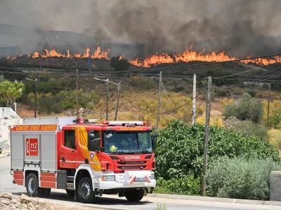 A firefighting vehicle drives by as smoke and flames rise during deadly wildfires affecting Almeria province, in Alfaix, Spain, July 10, 2026. REUTERS/Stringer