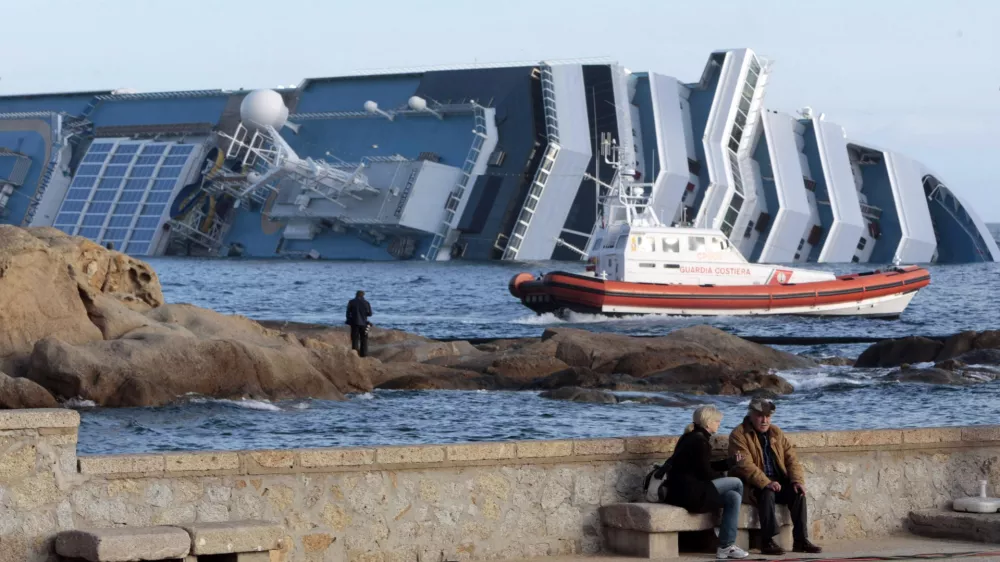 The cruise ship Costa Concordia lies on its side off the tiny Tuscan island of Giglio, Italy, Friday, Jan. 20, 2012. The $450 million Costa Concordia was carrying more than 4,200 passengers and crew when it slammed into well-marked rocks off the island of Giglio after the captain made an unauthorized diversion from his programmed route. The ship then keeled over on its side. (AP Photo/Gregorio Borgia)