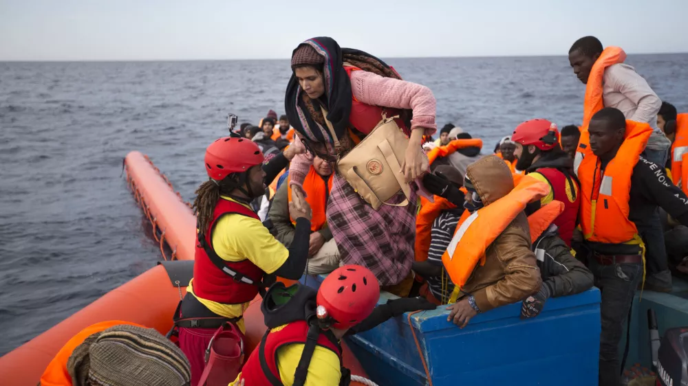 FILE- In this Friday, Feb. 3, 2017 file photo, migrants and refugees are assisted by members of the Spanish NGO Proactiva Open Arms, as they crowd on board of a wooden boat sailing out of control in the Mediterranean Sea about 21 miles north of Sabratha, Libya. Europeans have made a wrong, and dangerous, turn on the Mediterranean as they try to slow the ever-growing number of migrants crossing the sea by looking for help from Libya, a country in chaos that is the jumping-off point for the hazardous journey, Amnesty International said in a report released Thursday, July 6, 2017. (AP Photo/Emilio Morenatti, File)