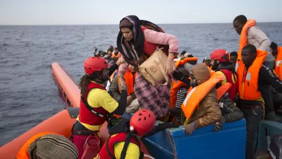 FILE- In this Friday, Feb. 3, 2017 file photo, migrants and refugees are assisted by members of the Spanish NGO Proactiva Open Arms, as they crowd on board of a wooden boat sailing out of control in the Mediterranean Sea about 21 miles north of Sabratha, Libya. Europeans have made a wrong, and dangerous, turn on the Mediterranean as they try to slow the ever-growing number of migrants crossing the sea by looking for help from Libya, a country in chaos that is the jumping-off point for the hazardous journey, Amnesty International said in a report released Thursday, July 6, 2017. (AP Photo/Emilio Morenatti, File)