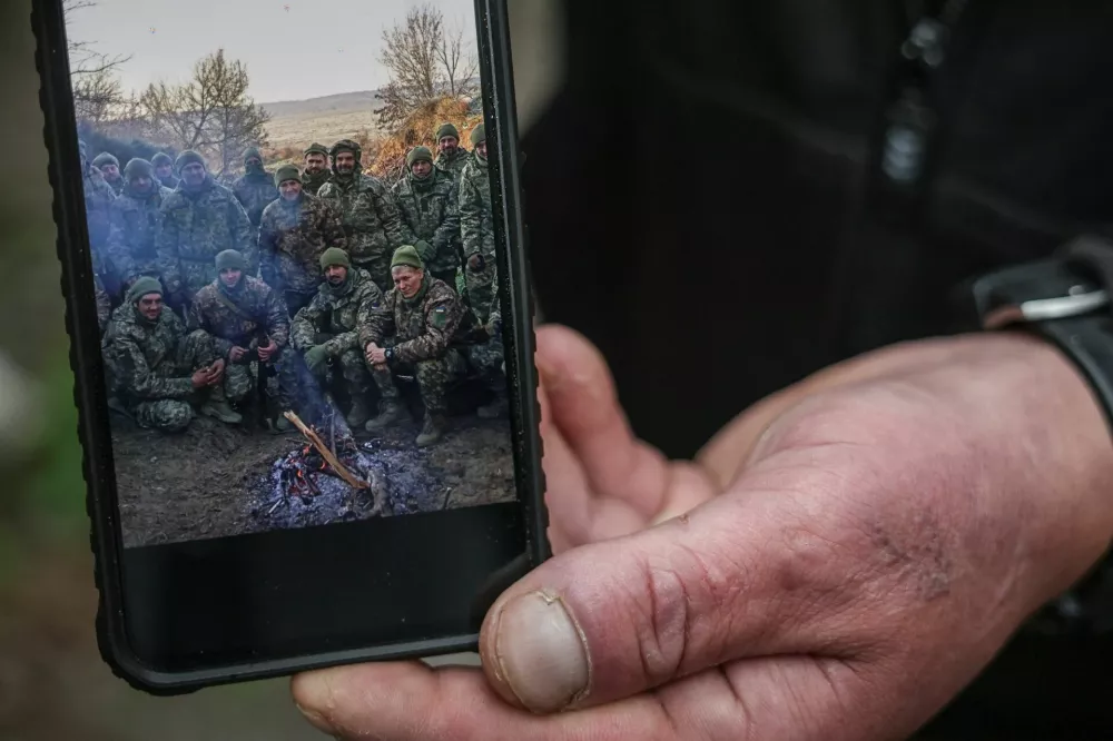 Serhii Krynitskyi, 42, a serviceman of the 24th Separate Mechanized Brigade of the Ukrainian Armed Forces, who spent 346 days at an isolated frontline position in the town of Chasiv Yar, Donetsk region, shows a photo of him with fellow soldiers in the beginning of his service in November 2024, on his first day back on duty after recovery, amid Russia's attack on Ukraine, in the frontline city of Kramatorsk in Donetsk region, Ukraine, May 27, 2026. REUTERS/Alina Smutko