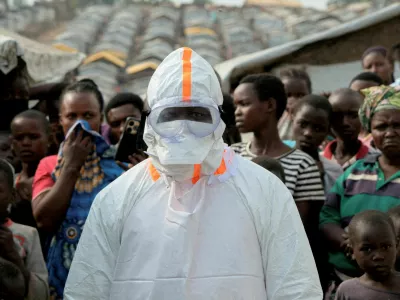 FILE PHOTO: A health worker in personal protective equipment stands near displaced people waiting for the burial of suspected Ebola victims at the Kigonze displaced persons camp, one month after an outbreak was declared, in Bunia, eastern Democratic Republic of Congo, June 18, 2026. REUTERS/Gradel Muyisa Mumbere/File Photo