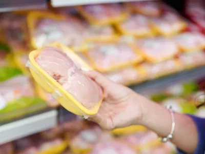 meat in food store. Woman choosing packed fresh chicken meat in supermarket.