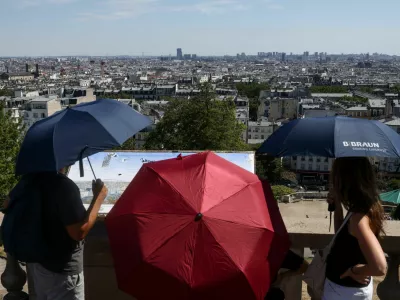 People shelter under umbrellas in front of the Sacre Coeur in Montmartre during high temperatures amid a heatwave in Paris, France, July 12, 2026. REUTERS/Tom Nicholson