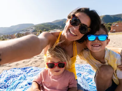 Happy beautiful asian family having fun at the beach during summertime vacation - Chinese mother and mixed race asian children spending time together at the sea, concepts about family, motherhood and diversity