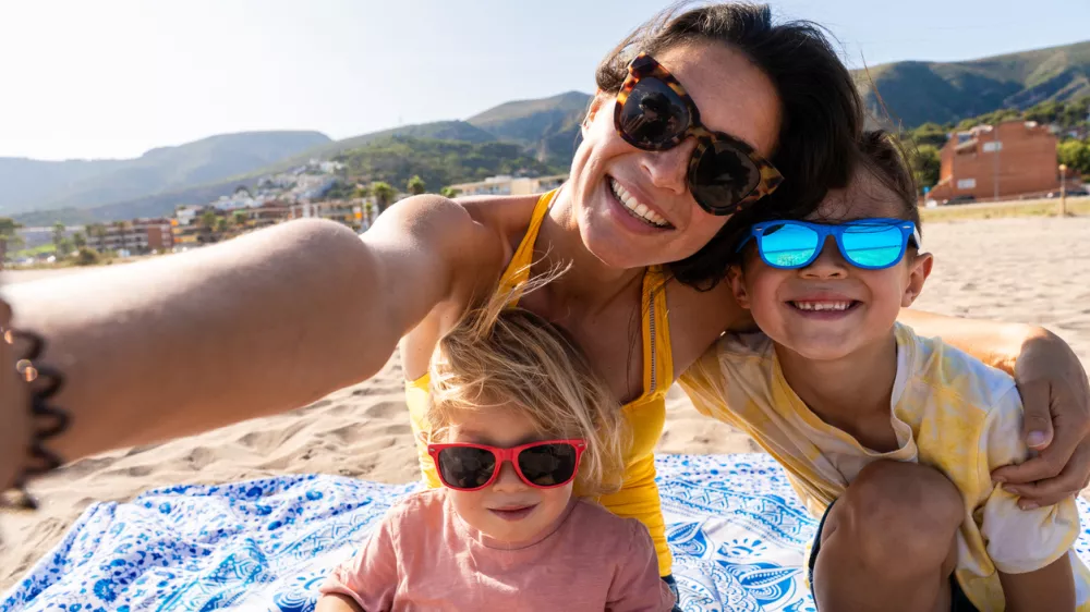 Happy beautiful asian family having fun at the beach during summertime vacation - Chinese mother and mixed race asian children spending time together at the sea, concepts about family, motherhood and diversity