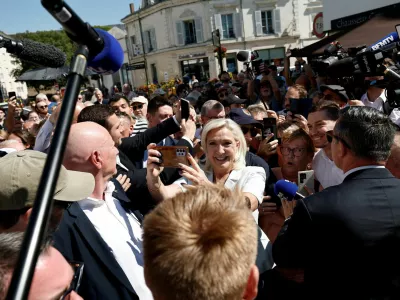 FILE PHOTO: French far-right leader Marine Le Pen and Jordan Bardella, president of the French far-right Rassemblement National (National Rally - RN) political party, make selfies with supporters surrounded by journalists in La Fleche, in the Sarthe department, France, July 8, 2026. REUTERS/Benoit Tessier/File Photo