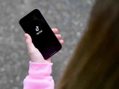 FILE PHOTO: A teenager poses for a picture with a phone displaying the TikTok logo, in Bonn, Germany, February 20, 2026. REUTERS/Jana Rodenbusch/File Photo