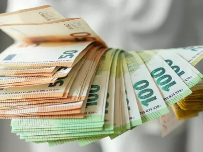 Hand holding large fan of euro banknotes in 50, 100, and 200 denominations, concept of abundance, wealth, success and financial prosperity
