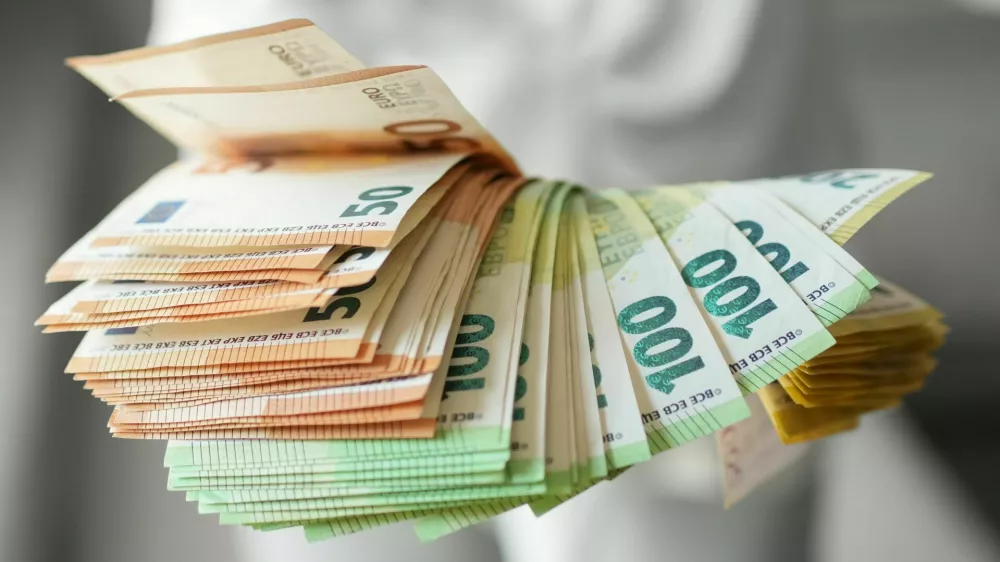 Hand holding large fan of euro banknotes in 50, 100, and 200 denominations, concept of abundance, wealth, success and financial prosperity