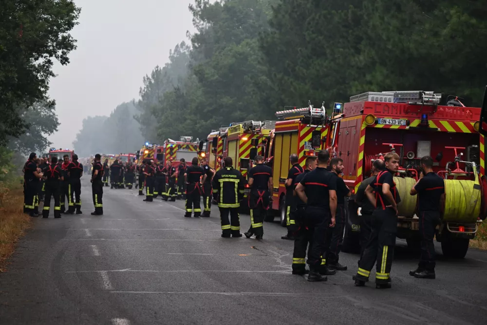 Firefighters wait on a road near Lacanau, southwestern France, Saturday, July 25, 2026. (AP Photo/Emma Da Silva)