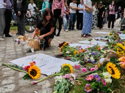 People stop by the memorial site commemorating the victims near the scene where a car rammed into a crowd at the Pride March in Berlin, Germany, Sunday, July 26, 2026. (AP Photo/Markus Schreiber)