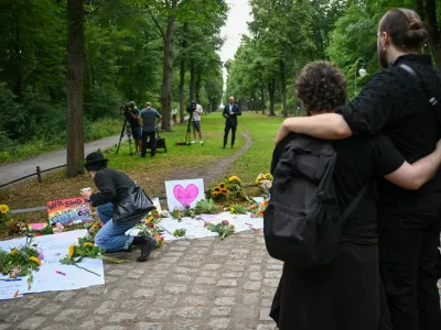 People embrace each other next to tributes at Tiergarten park following a deadly incident in which a vehicle crashed into a crowd near Berlin's annual Christopher Street Day Pride parade on Saturday evening, leaving multiple people injured and the parade called off, in Berlin, Germany, July 26, 2026. REUTERS/Annegret Hilse