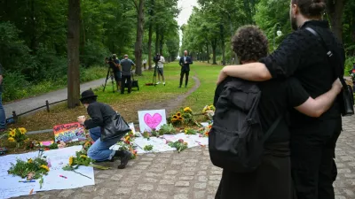 People embrace each other next to tributes at Tiergarten park following a deadly incident in which a vehicle crashed into a crowd near Berlin's annual Christopher Street Day Pride parade on Saturday evening, leaving multiple people injured and the parade called off, in Berlin, Germany, July 26, 2026. REUTERS/Annegret Hilse