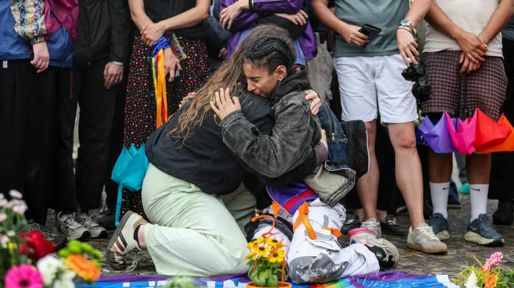 People hug each other as they gather at Brandenburg Gate, after a deadly incident in which a vehicle crashed into a crowd near Berlin's annual Christopher Street Day Pride parade on Saturday evening, leaving multiple people injured and the parade called off, in Berlin, Germany, July 26, 2026. REUTERS/Maryam Majd