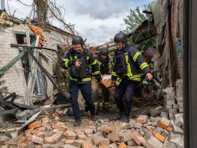 Rescuers carry a body that they removed from under the rubble of an private house following a drone attack from Russia, in Kharkiv, Ukraine, Sunday, July 26, 2026. (AP Photo/Andrii Marienko)