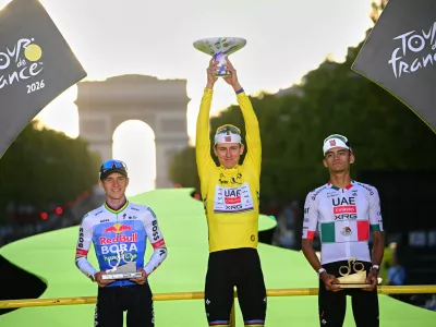 Slovenia's Tadej Pogacar, wearing the overall leader's yellow jersey, celebrates on the podium after winning the Tour de France cycling race alongside Belgium's Remco Evenepoel, second, and Mexico's Isaac Del Toro, third, in Paris, Sunday, July 26, 2026. (AP Photo/Bernard Papon/Pool Photo via AP)