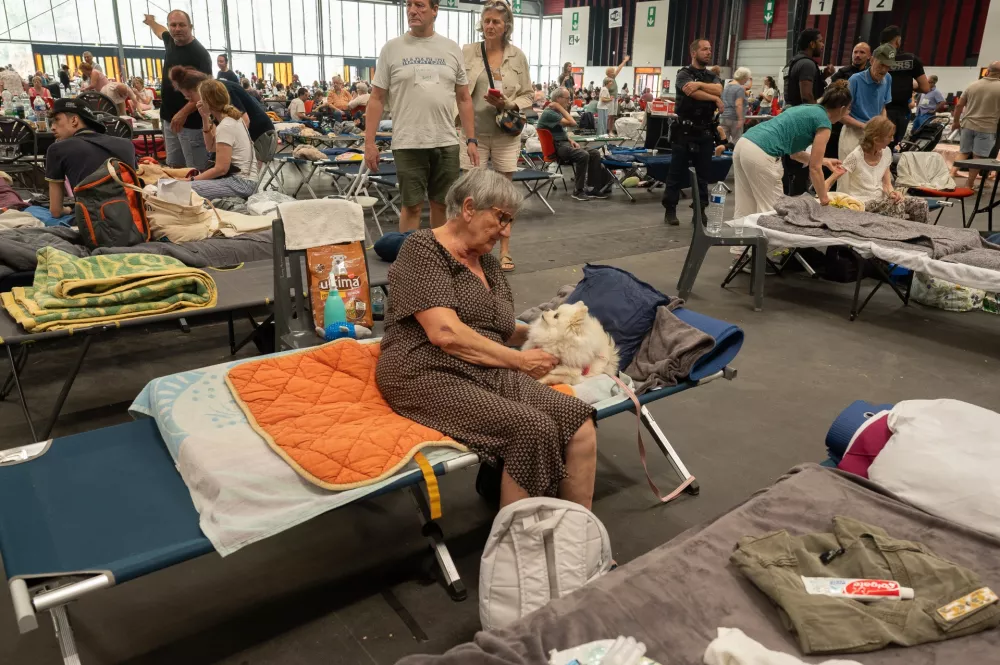 An elderly woman caresses her pet dog at an emergency shelter set up in the Bordeaux Exhibition Centre in Bordeaux, France, for those that had to leave their homes outside town due to the raging wildfires, Sunday, July 26, 2026. (AP Photo/Caroline Blumberg)