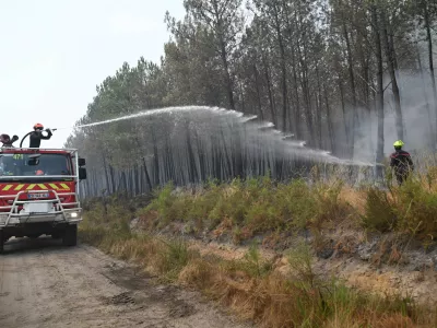 Firefighters suppress a blaze in a forest as wildfires rage near Le Las, outside Bordeaux, France, Monday, July 27, 2026. (AP Photo/Emma Da Silva)
