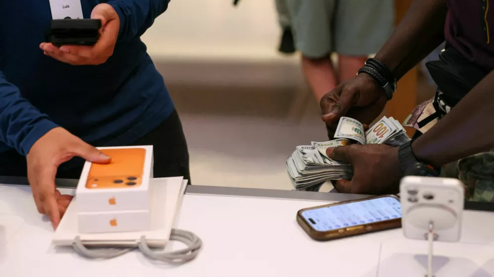FILE PHOTO: A man purchases an iPhone 17 series with cash at the Apple Store in New York City, U.S., September 19, 2025. REUTERS/Shannon Stapleton/File Photo