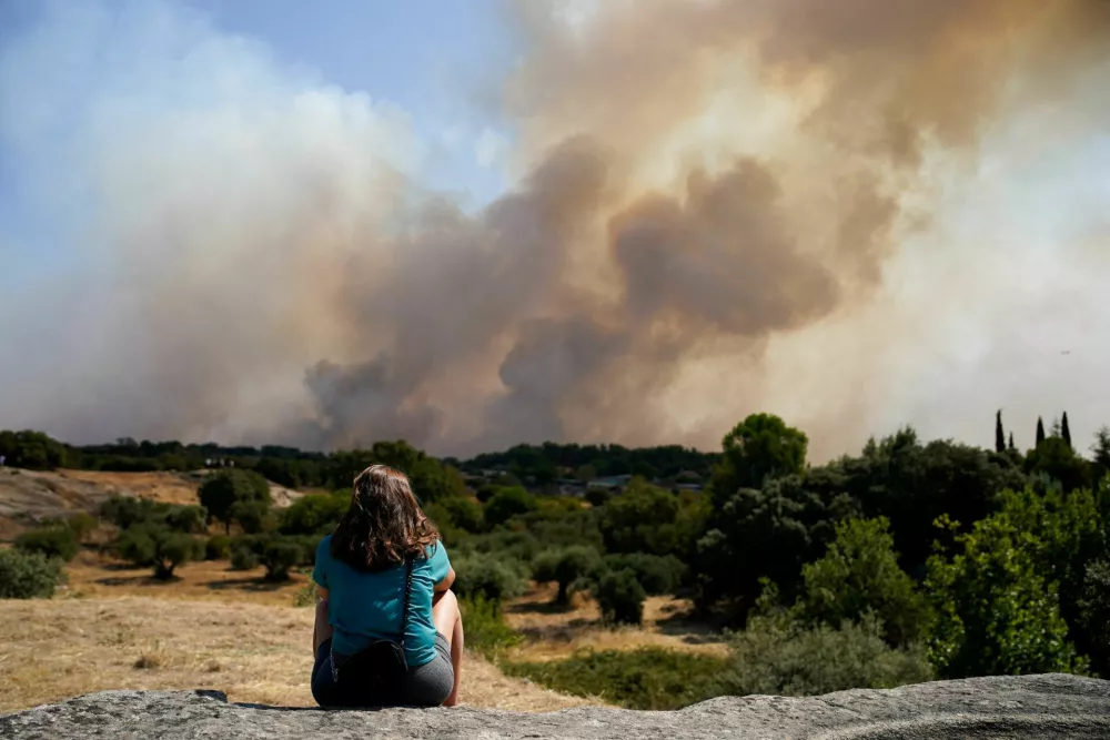 A woman looks as smoke rises from a wildfire in San Martin de Valdeiglesias, Community of Madrid, Spain, July 26, 2026. REUTERS/Ana Beltran   TPX IMAGES OF THE DAY