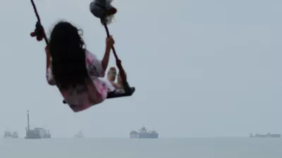 A girl swings along the shore as cargo ships and other commercial vessels appear anchored in the Strait of Hormuz off Bandar Abbas, Iran, Monday, July 27, 2026. (Razieh Poudat/ISNA via AP) / Foto: Razieh Poudat