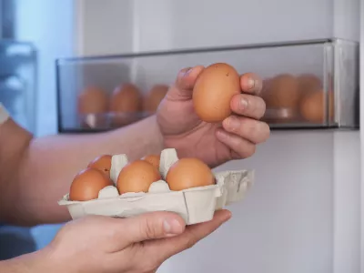 Close up of a man putting fresh eggs into refrigerator.