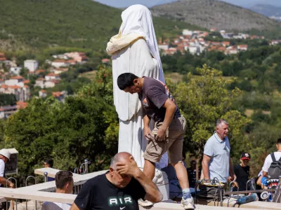 Volunteers clean the vandalized statue of the Virgin Mary, which has been covered with a white sheet, on Apparition Hill in Medjugorje, Bosnia, Tuesday, July 28, 2026. (AP Photo)